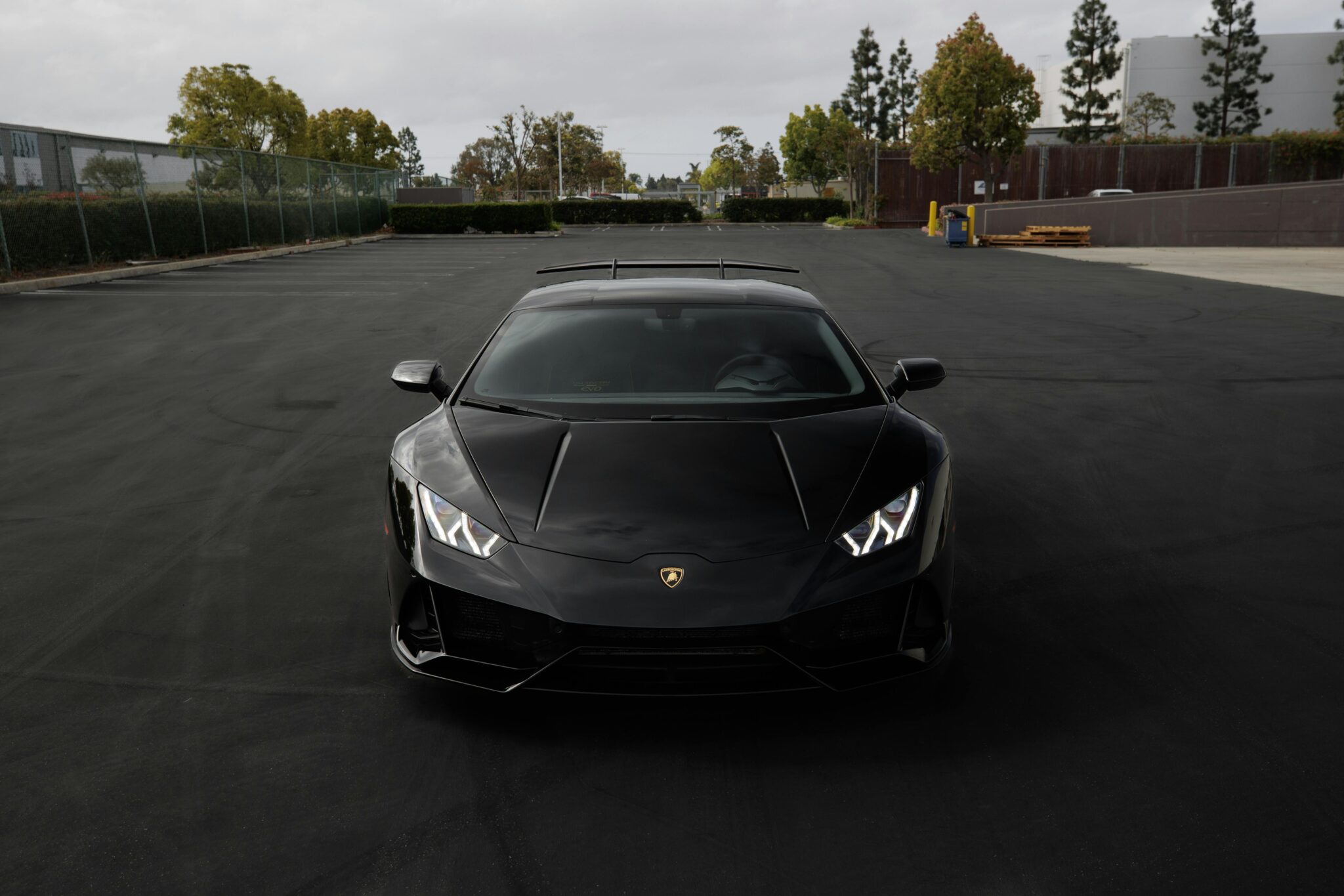 A stylish black Lamborghini Aventador parked in an empty outdoor parking lot showcasing automotive luxury.